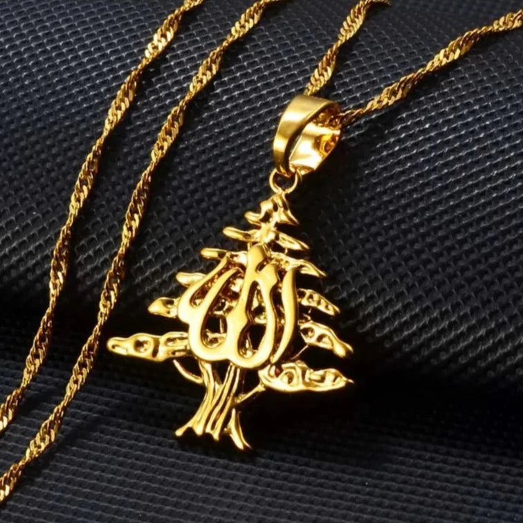 Gold cedar tree pendant necklace featuring intricate Arabic calligraphy, blending Lebanese heritage with artistic elegance for a bold statement piece.